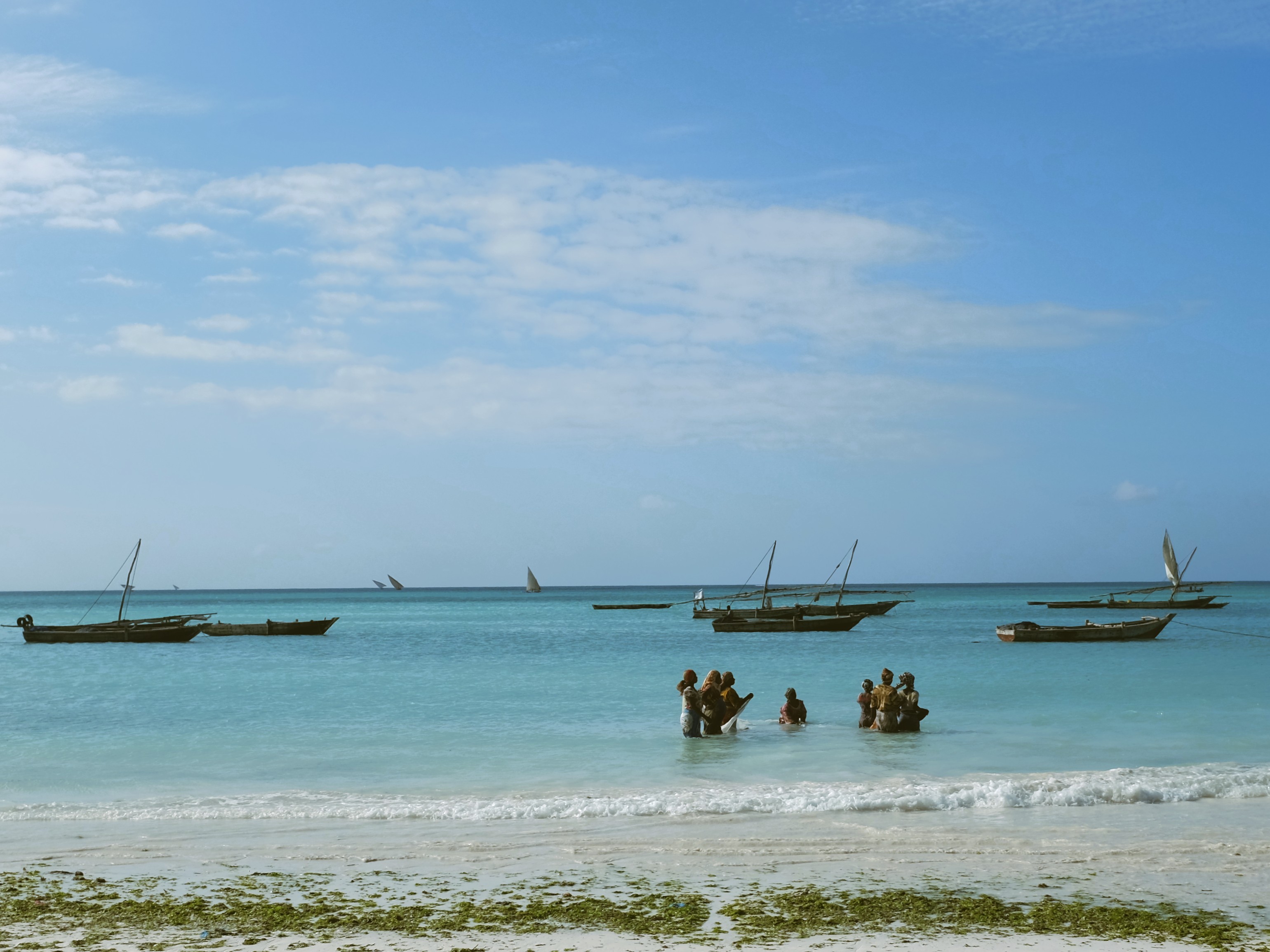 Small local boats and people in the shallow coastal water of Zanzibar. © EHBLX